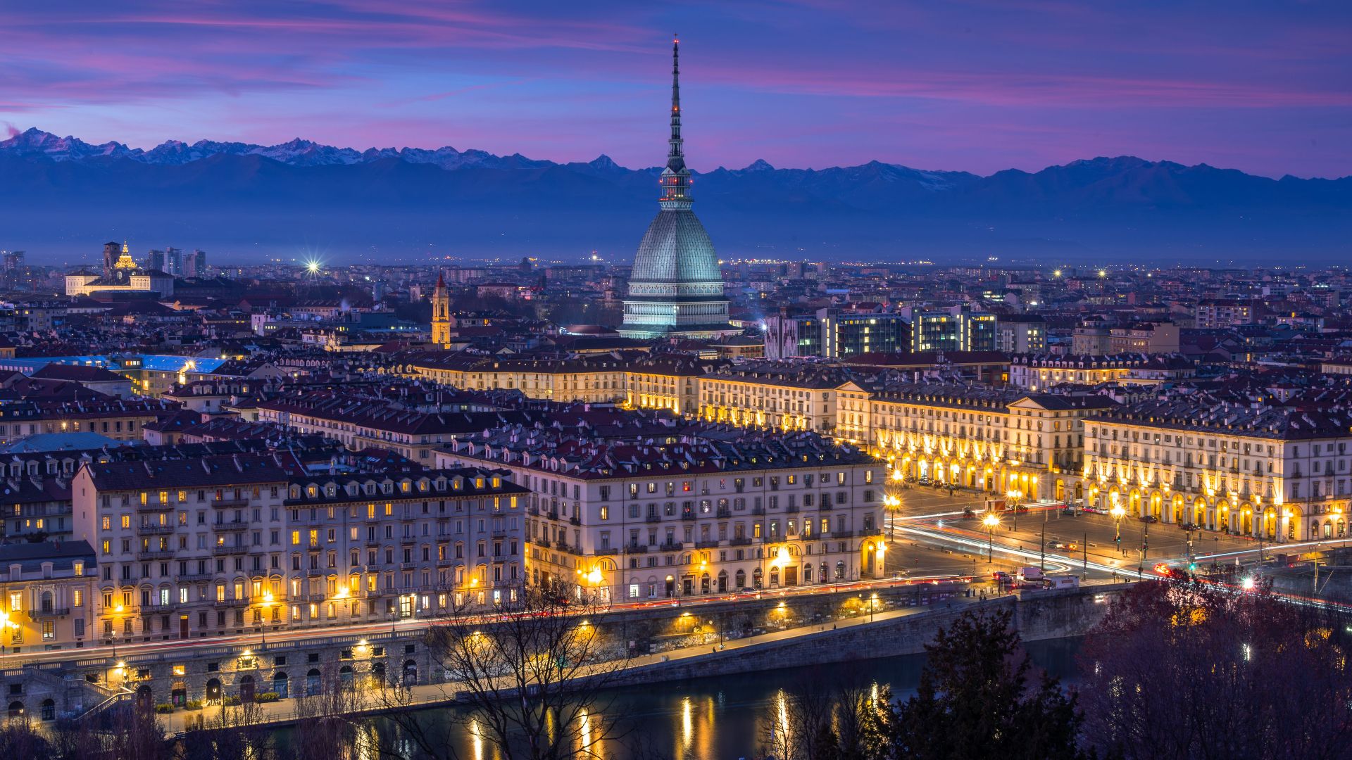 Stunning nighttime view of Turin's cityscape featuring the iconic Mole Antonelliana against a vibrant twilight sky.