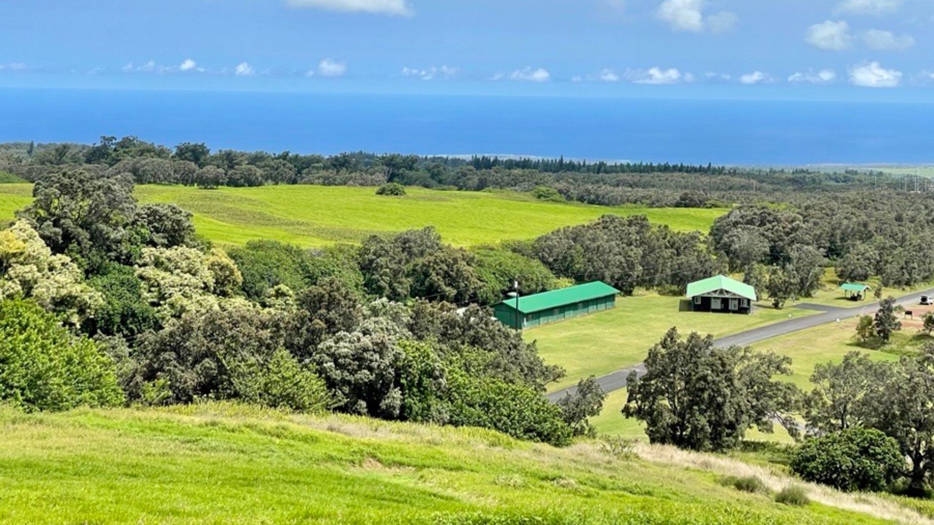 the visitor center of the Kahuku Unit of Hawai'i Volcanoes National Park seen from the top of a nearby cinder cone