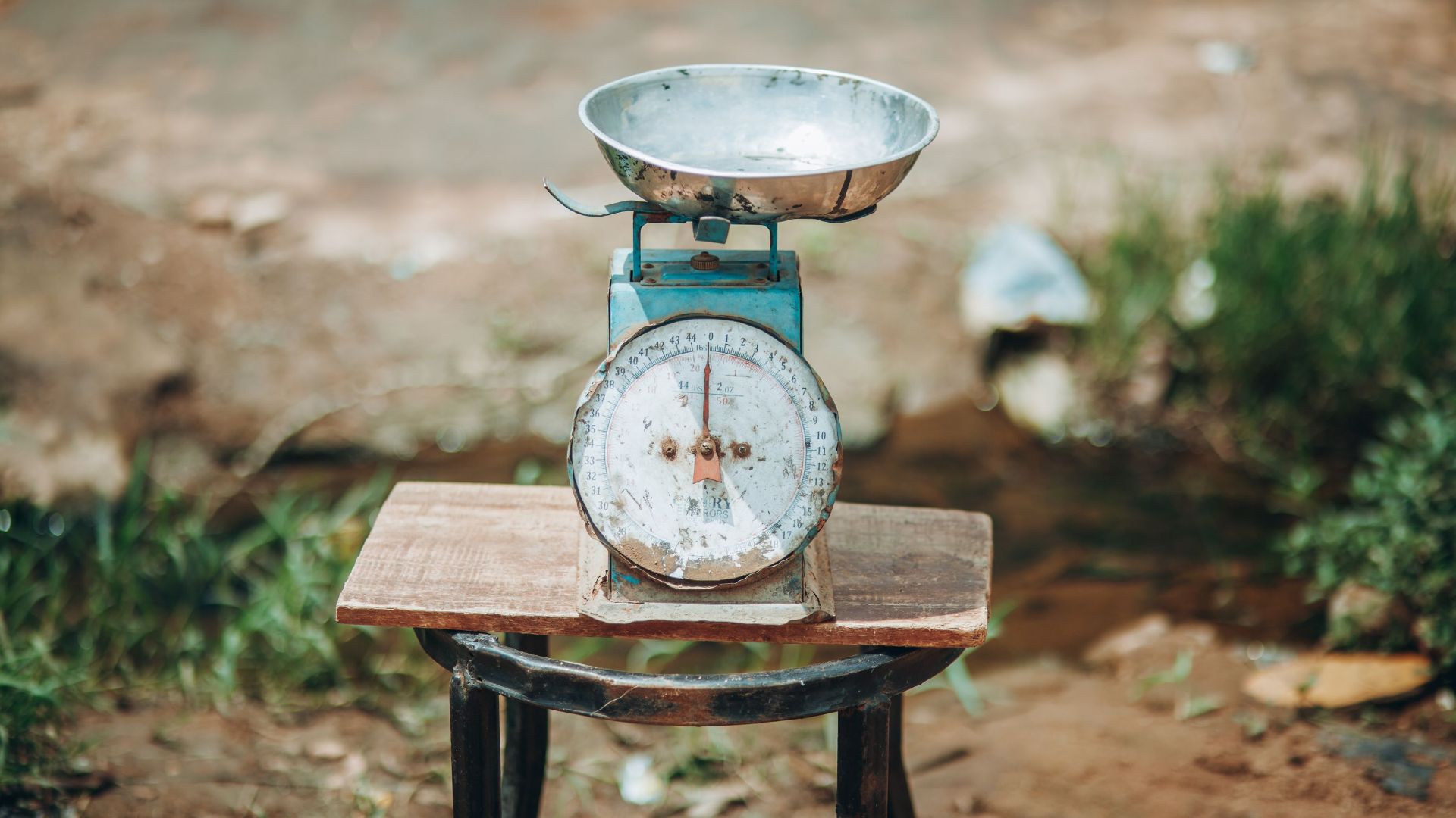 Close-up of an old-fashioned weighing scale placed outdoors on a wooden platform.