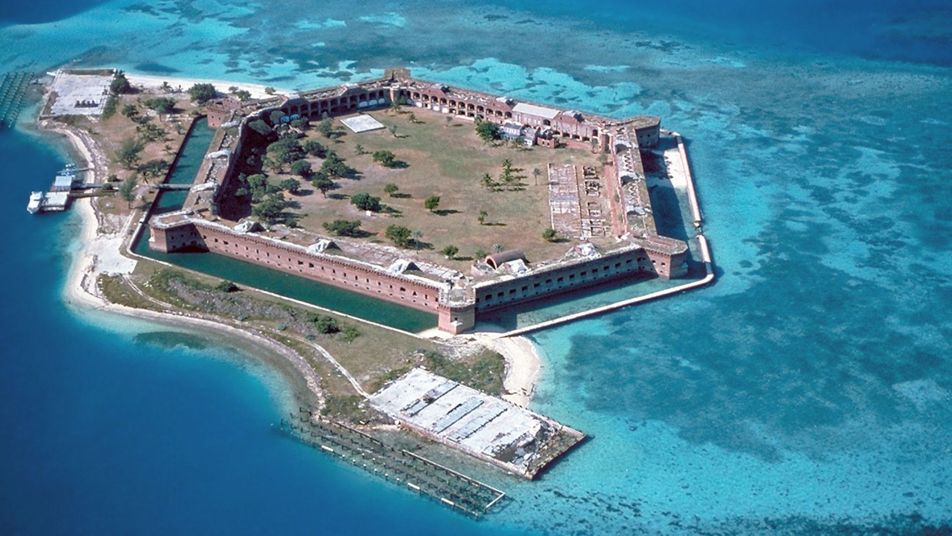 Fort Jefferson at the Dry Tortugas. The clear waters in shallow areas surrounding the fort, seen easily in the photo, are popular for snorkeling and scuba diving. Visible on the right side of the image is a breach of the sea wall caused by the direct stri