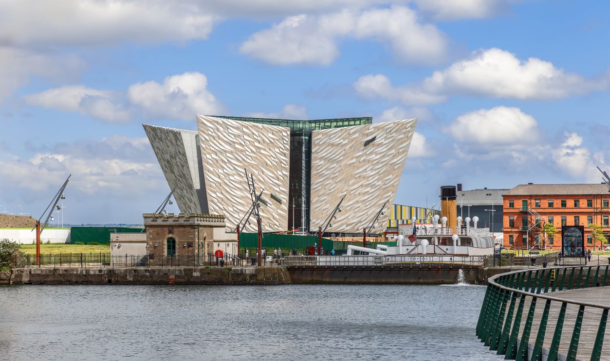 Belfast - Ireland. May 25, 2024: Titanic Museum in Belfast with its modern angular architecture, set against a bright blue sky and reflected in the surrounding water