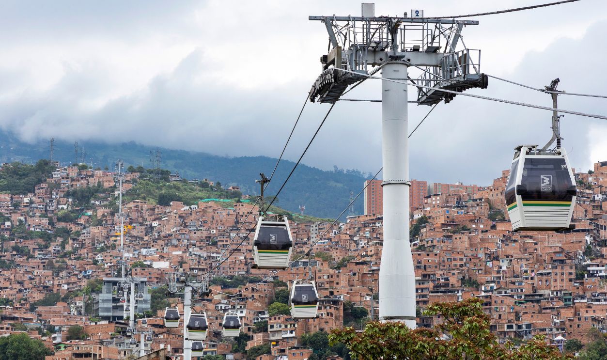 Medellin, Antioquia - Colombia. March 21, 2026. Cable cars of the Metrocable transportation system (Line J) soaring over the dense residential hillsides.