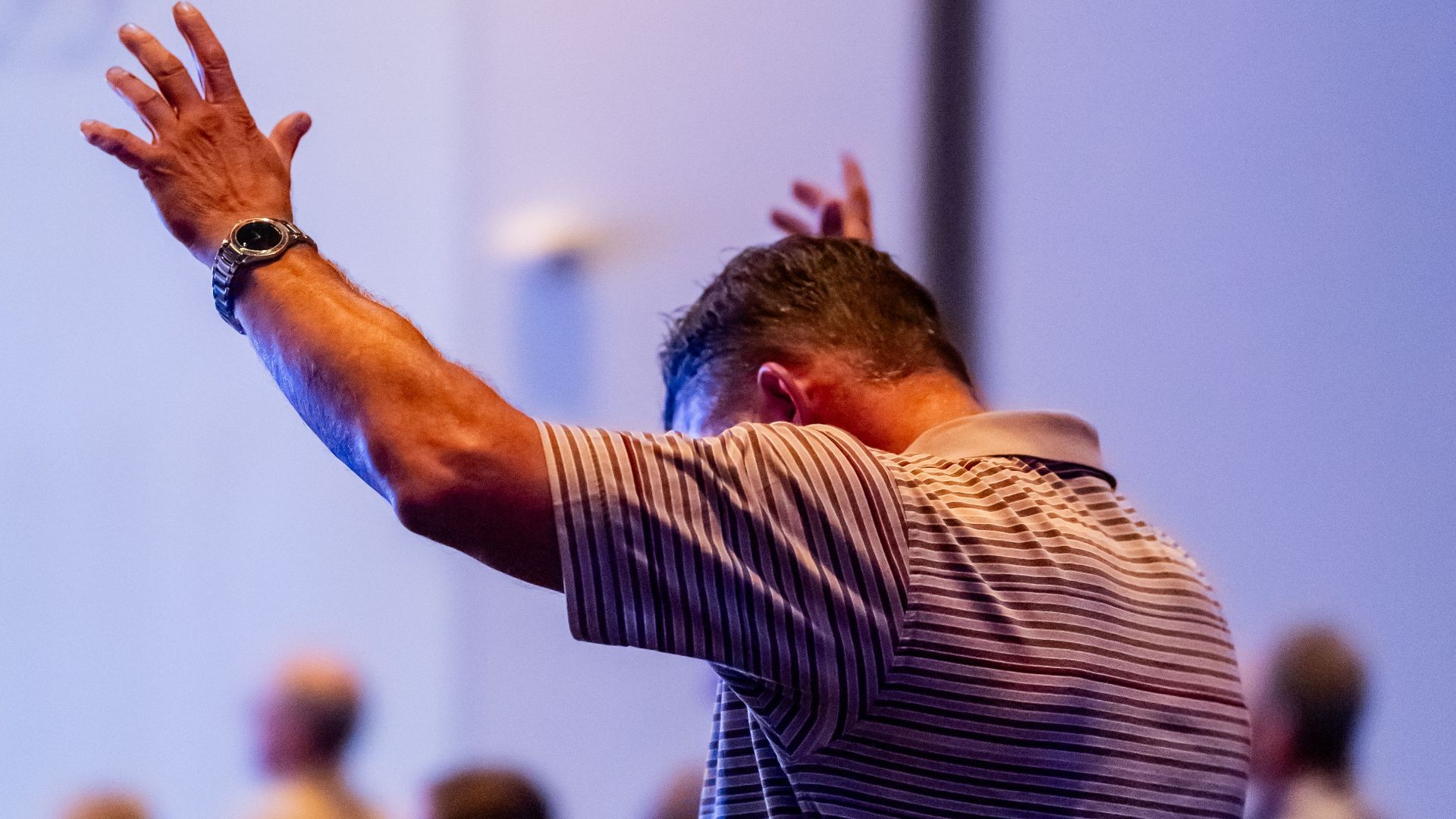 A man raises his arms during a vibrant church service, expressing worship.