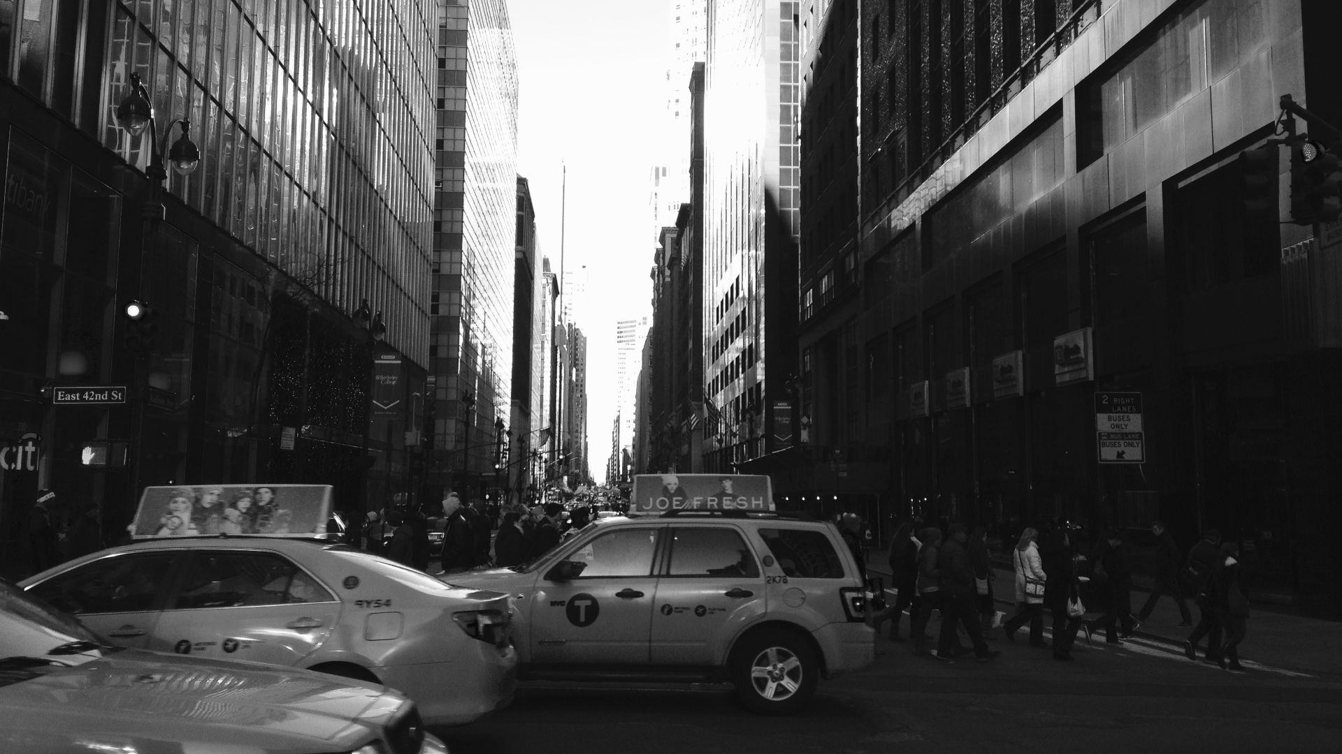A black and white image looking north on Madison Avenue when standing on East 42nd Street in New York City showing buildings and taxicabs