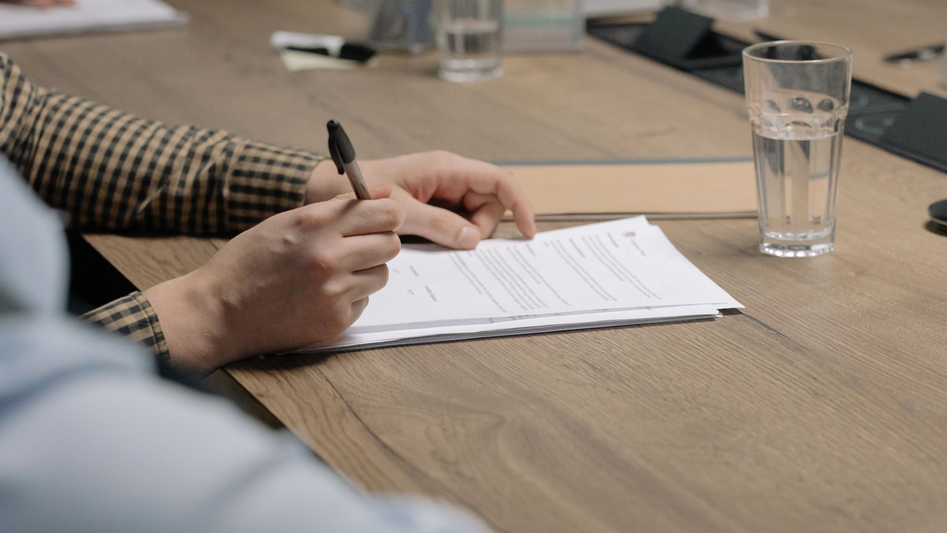 Professional setting of a business meeting with individuals signing documents on a conference table.