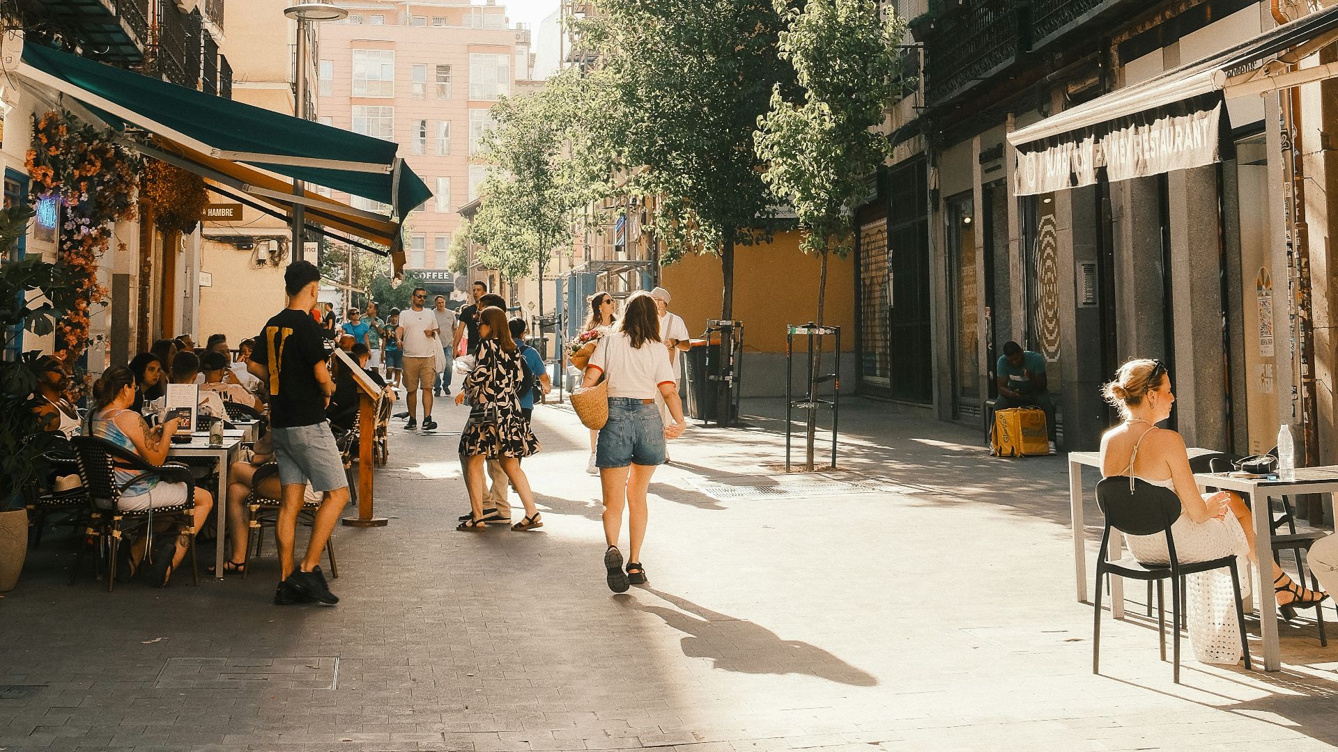 A group of people walking down a street next to tall buildings