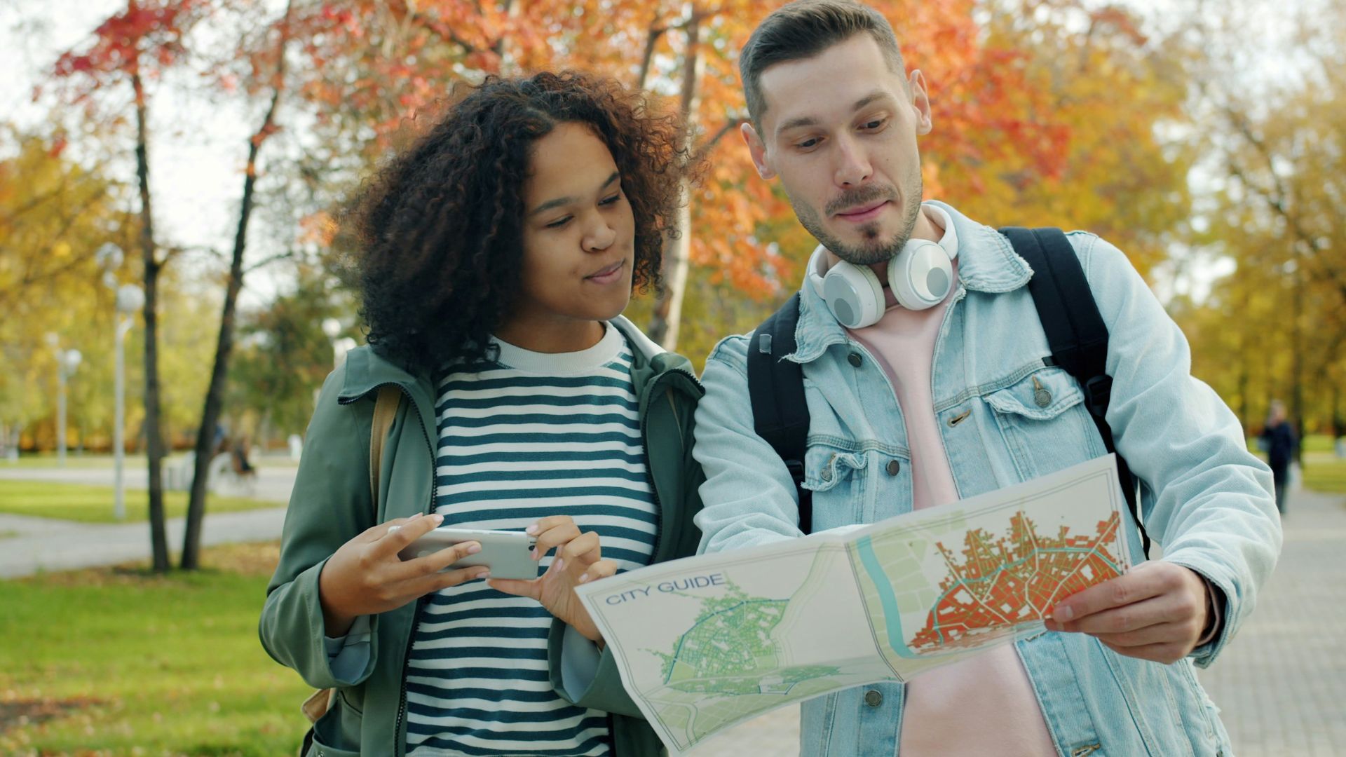 Couple looking at map in park during autumn