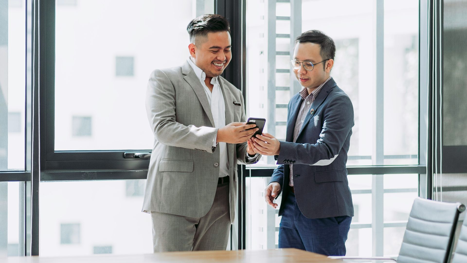 two businessmen looking at phone in office