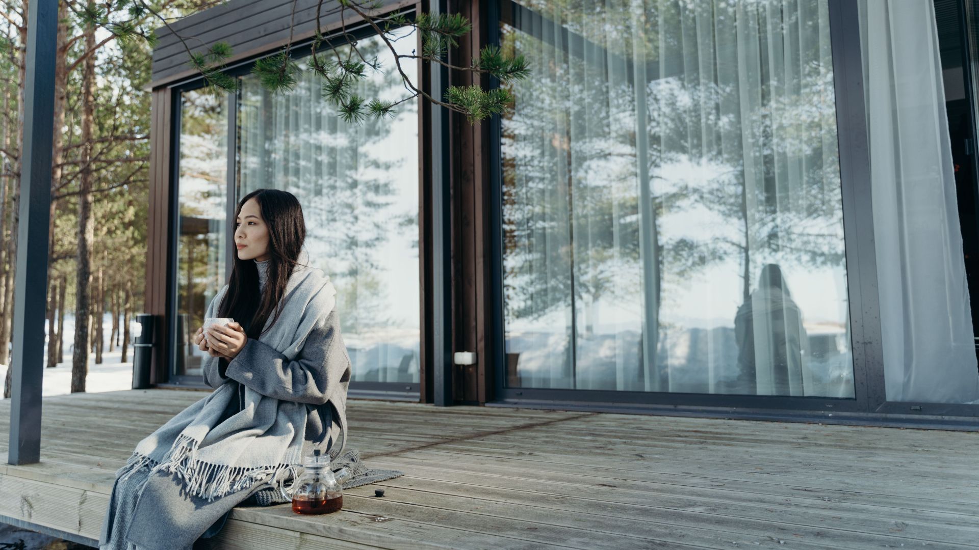 Asian woman enjoying a hot drink on a peaceful winter morning outdoors.