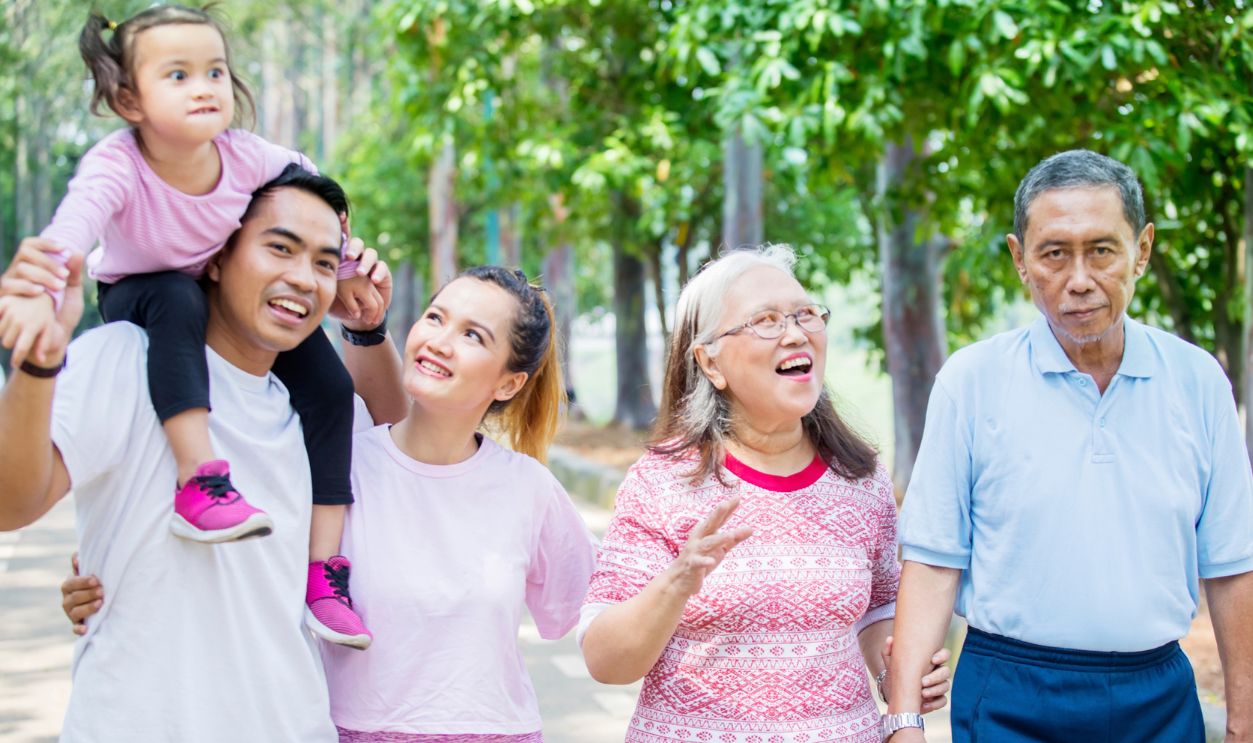 Three generation family smiling together at the camera while standing on the road
