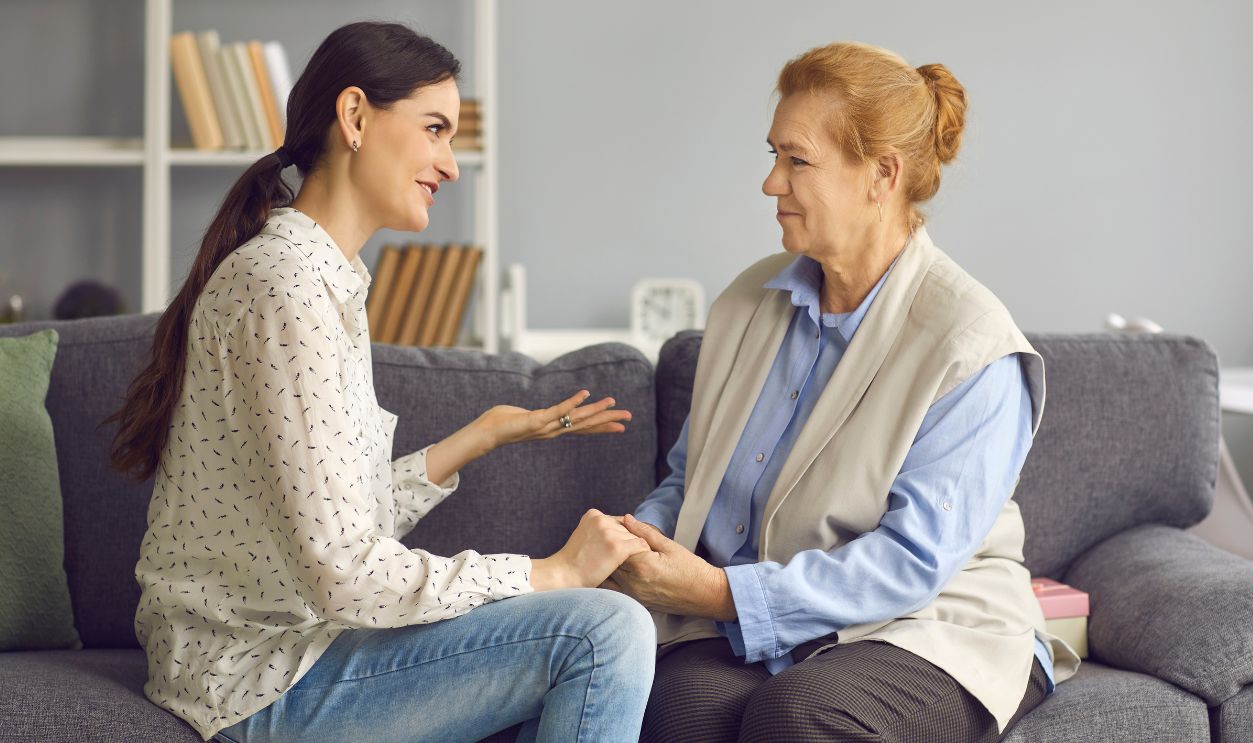 Grown-up daughter talking to senior mother. Happy daughter and friendly mother-in-law sitting on sofa and having sincere honest conversation. Mutual understanding, family supporting each other concept