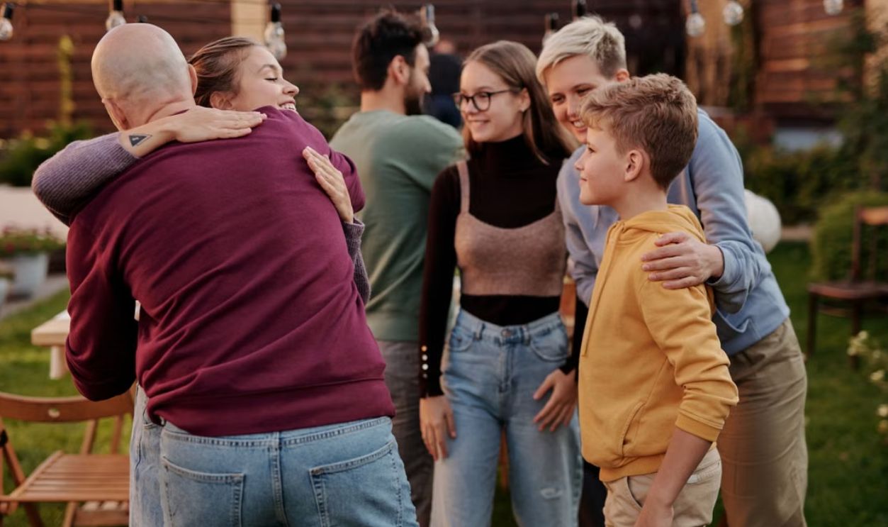 A joyful family gathering outdoors with hugs and smiles, symbolizing love and connection
