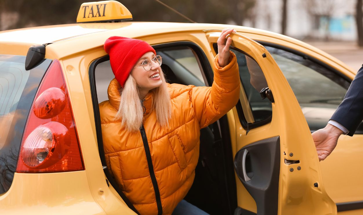 Driver helping young woman to get out of taxi