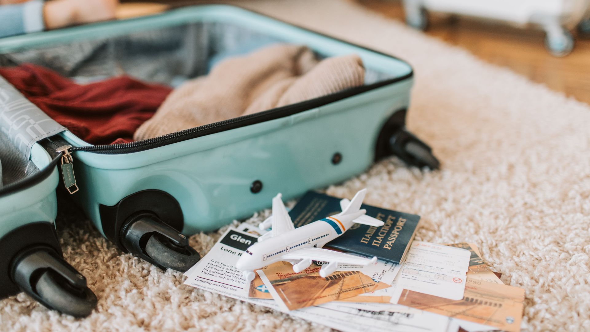 Close-up of an open suitcase with travel essentials like passport and tickets, ready for a journey.