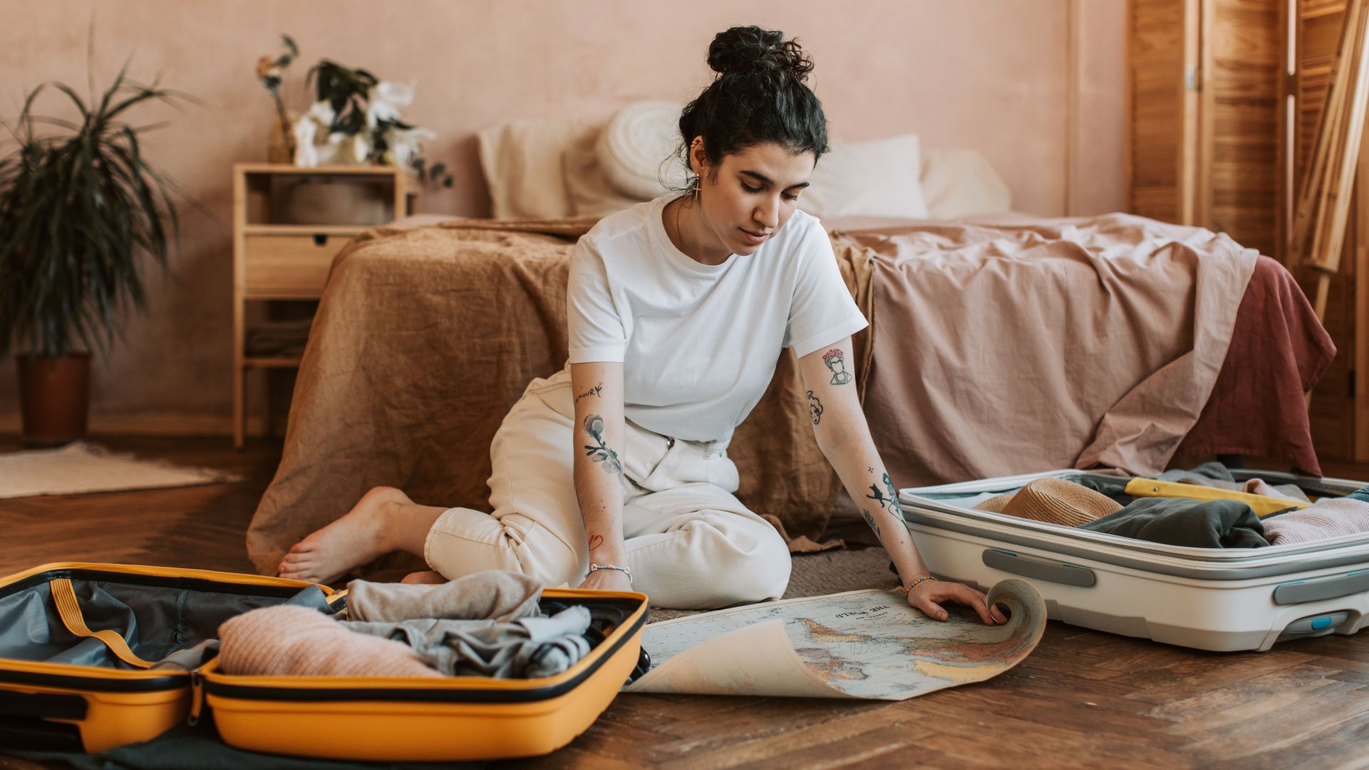 Young woman preparing for a trip, packing suitcases in a cozy bedroom setting.