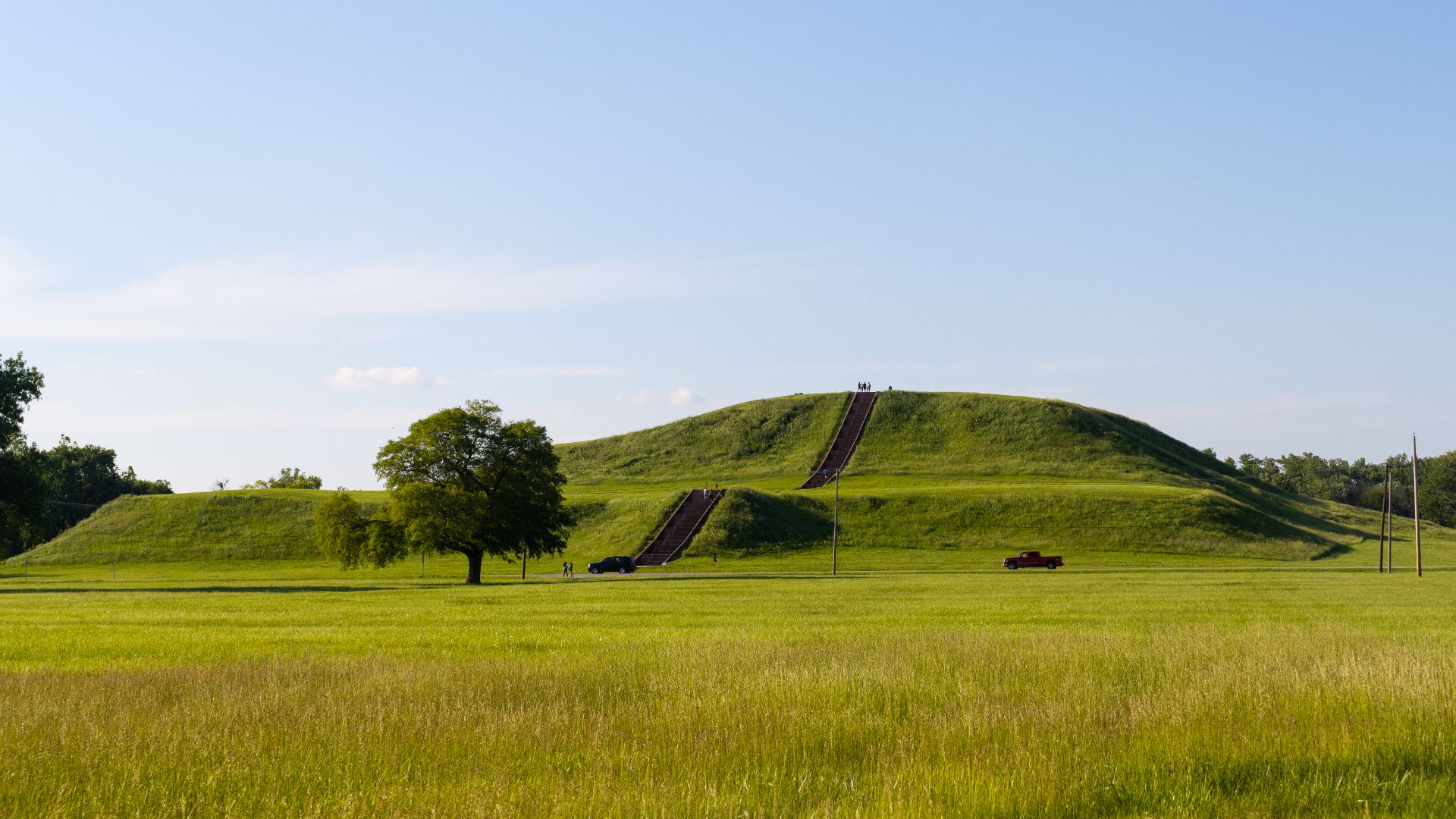 Photo taken in May 2024, facing the staircase side of Monks Mound.  People and vehicles can be used to judge the size of this ancient structure.