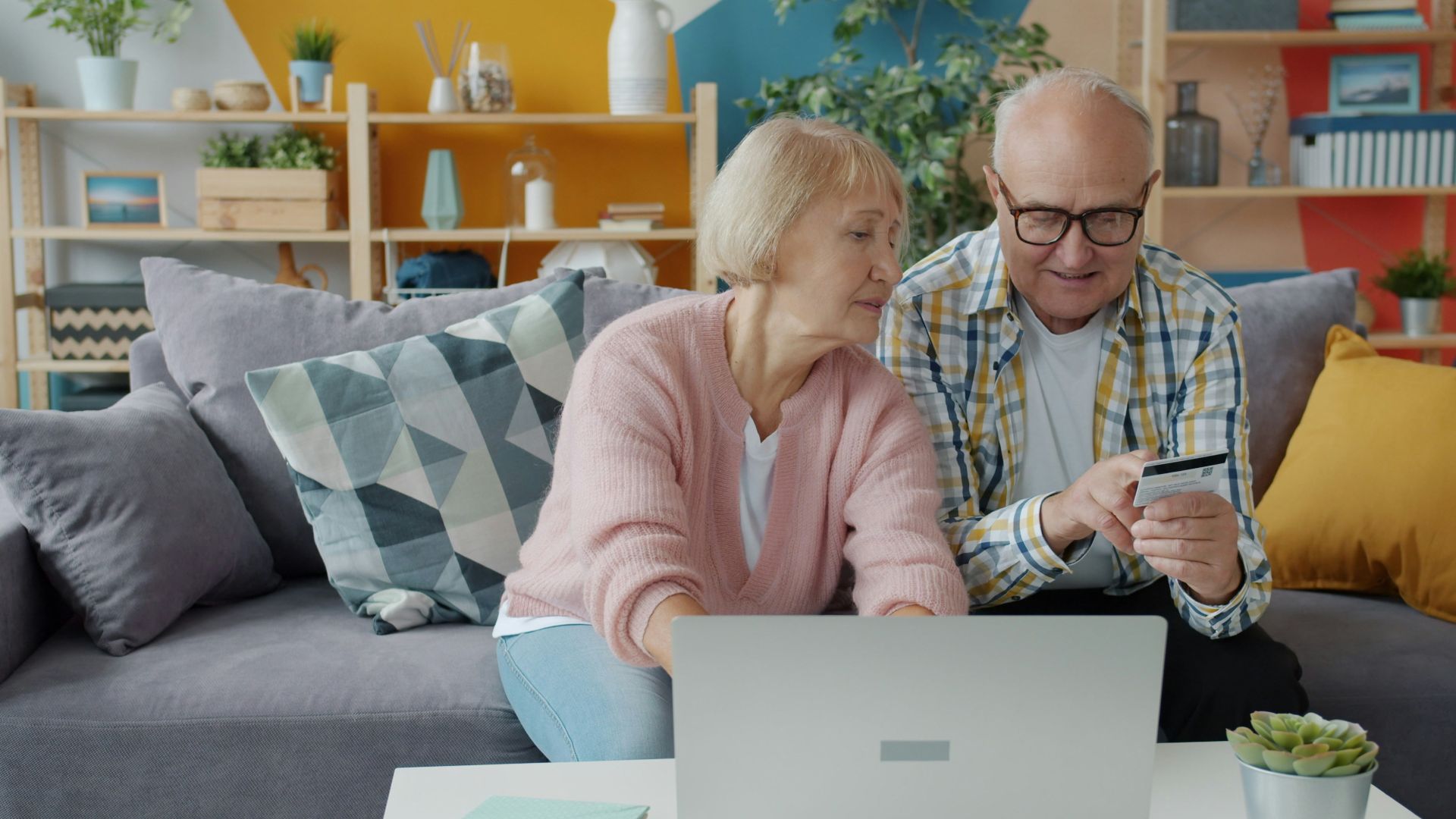 Elderly couple shopping online with credit card and laptop