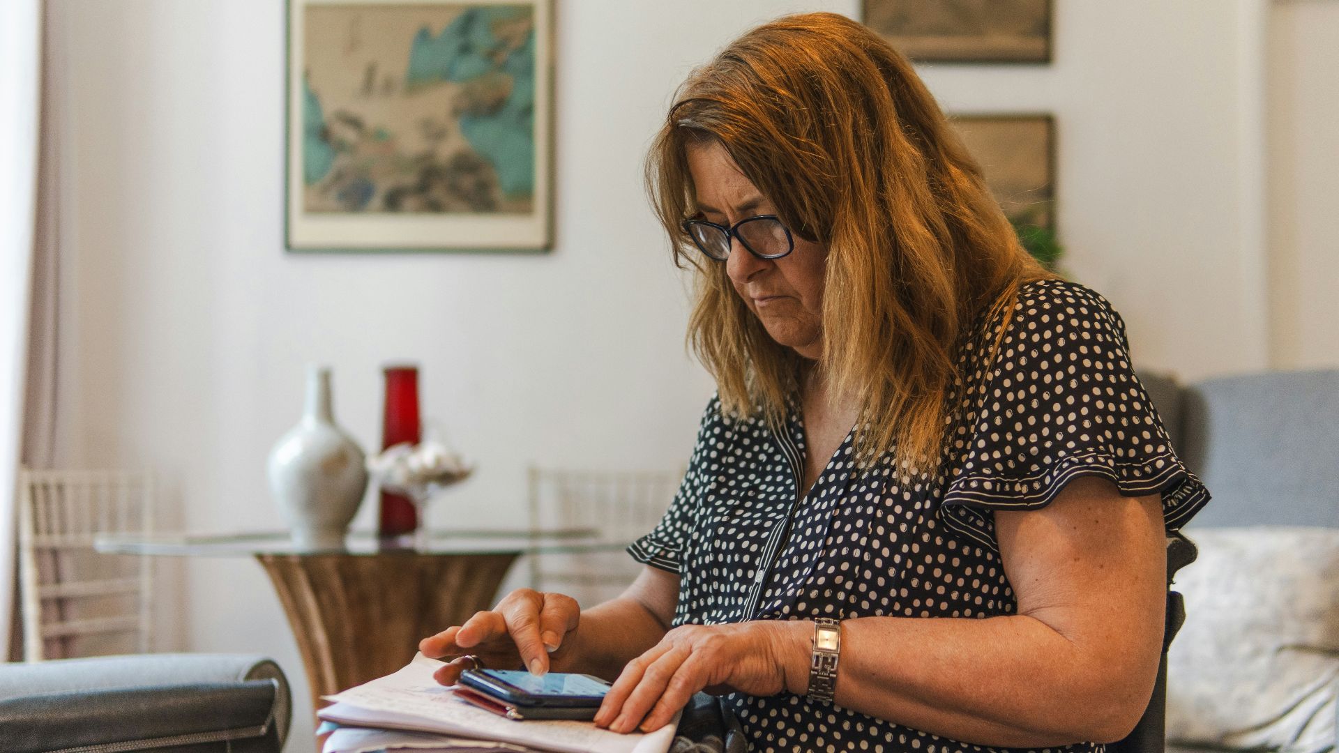 Woman looking at phone while writing on paper