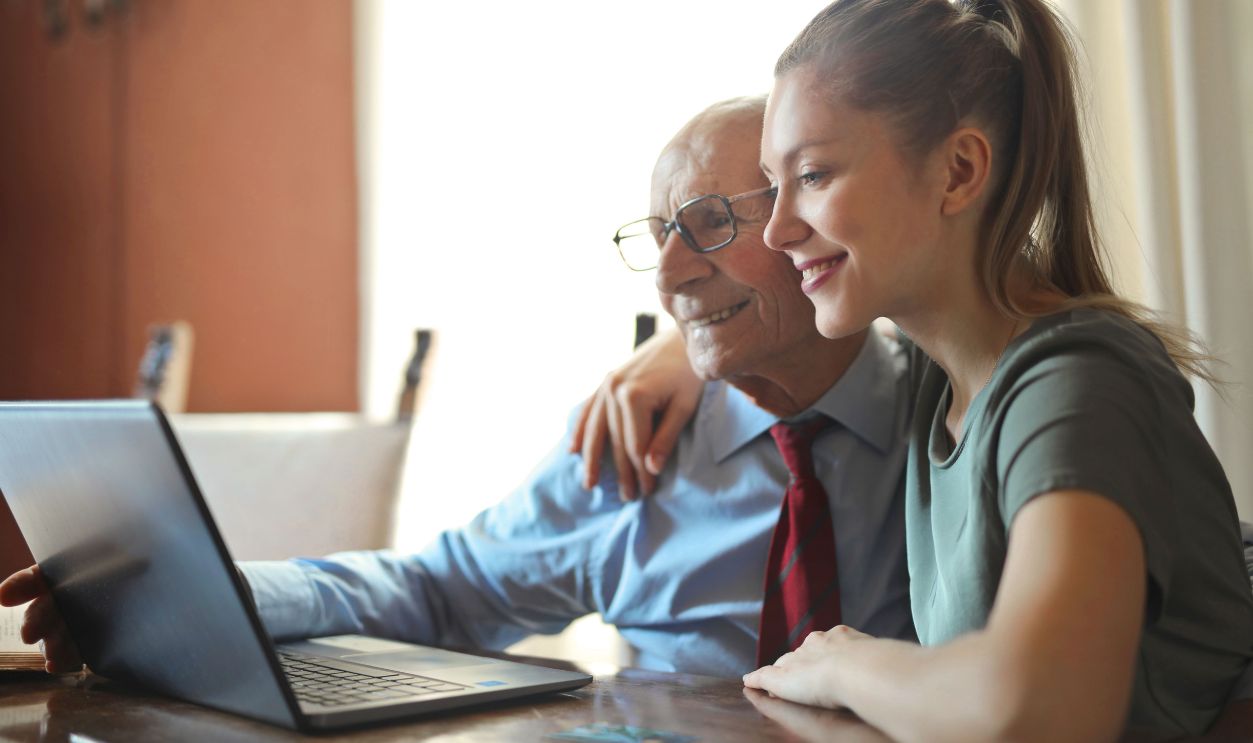 Elderly man and young woman bonding while using a laptop indoors