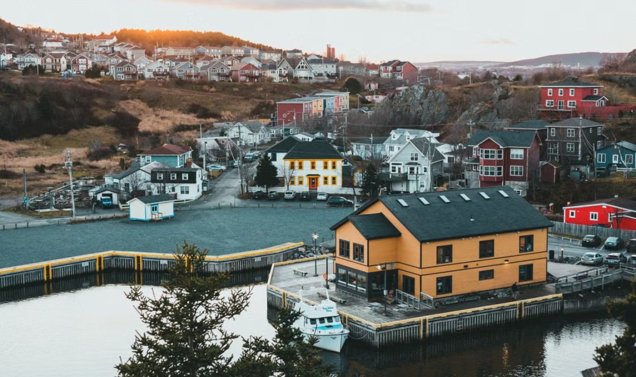 Charming harbor scene in St. John's, Newfoundland capturing colorful houses and serene waterfront at sunrise.