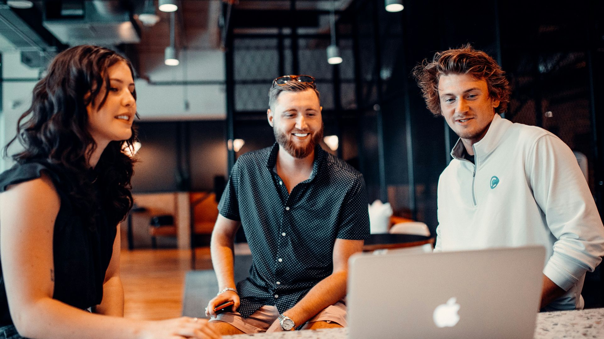 a group of people sitting around a laptop computer