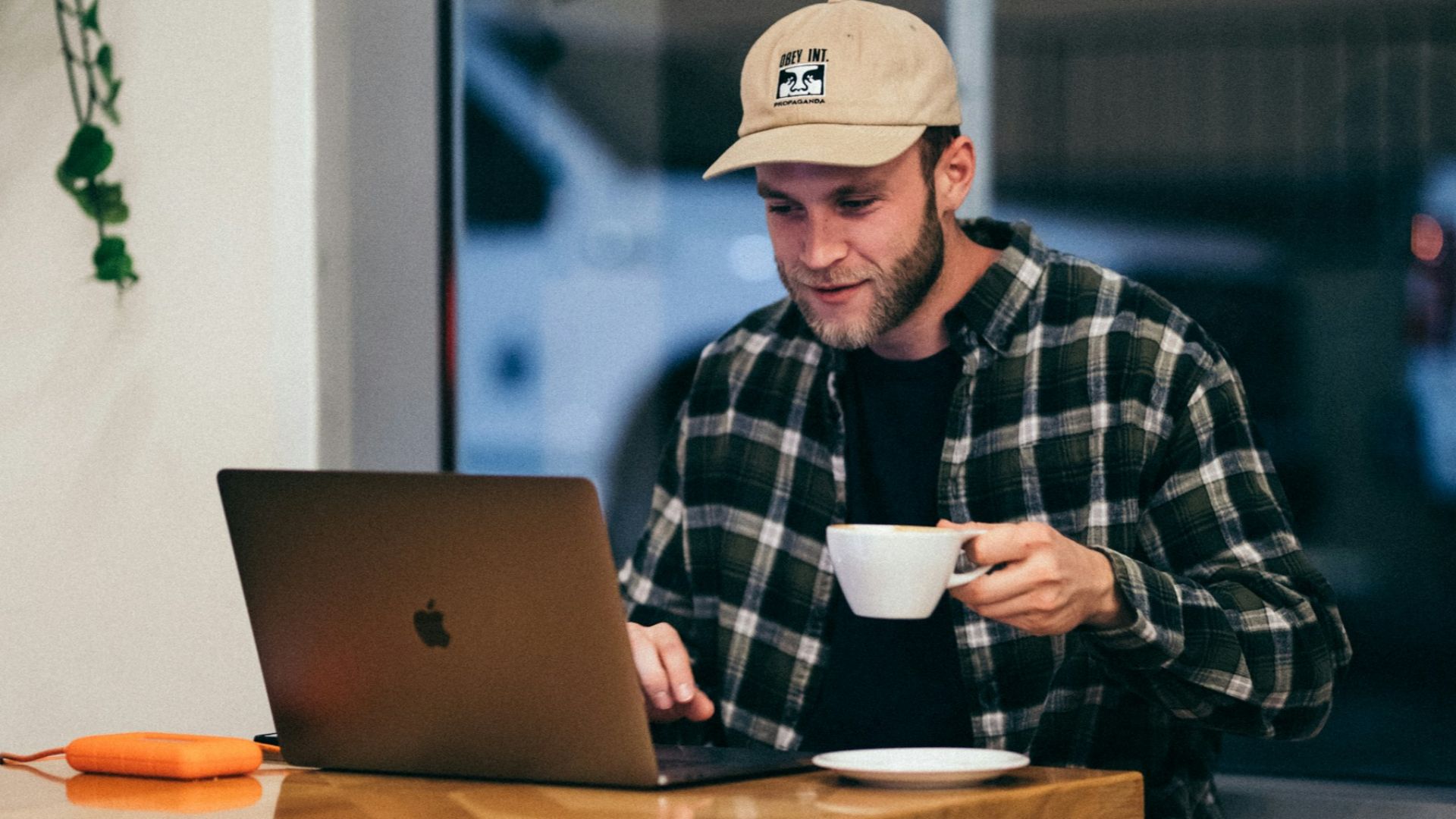 man sitting while having coffee and using laptop