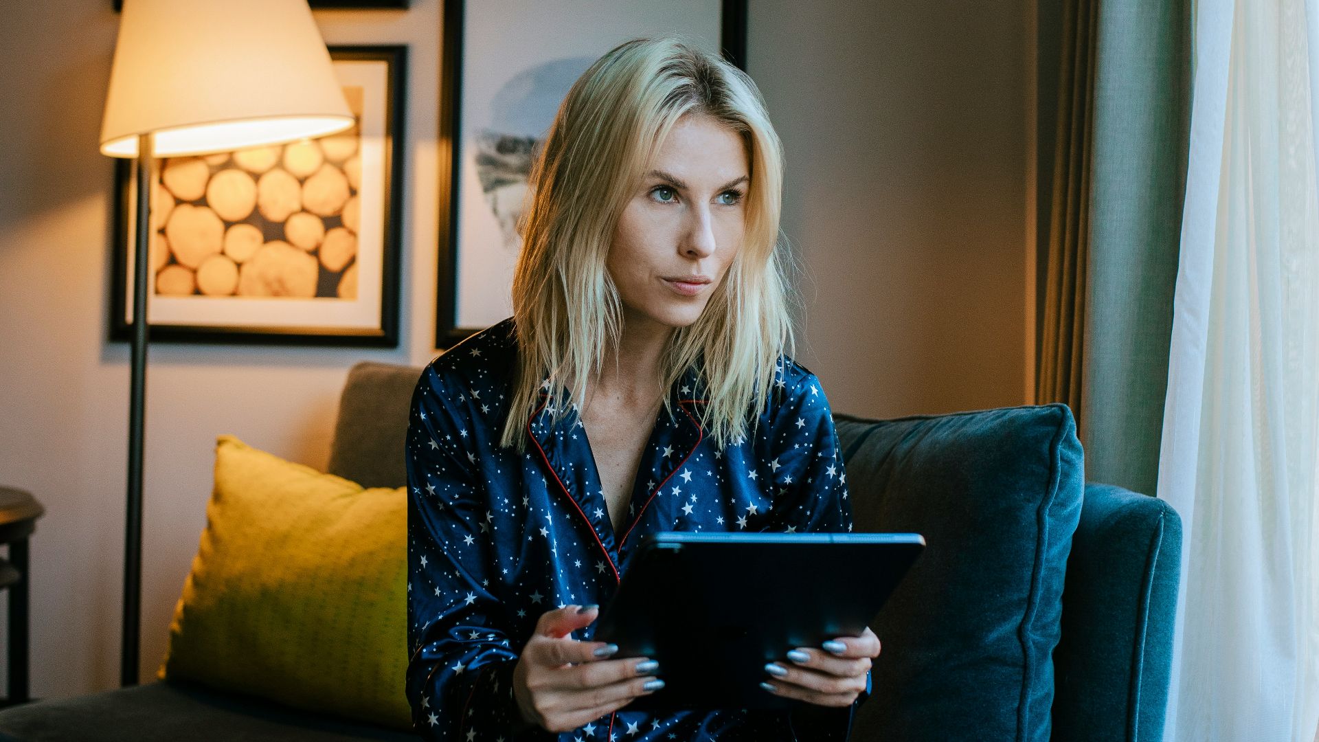 a woman sitting on a couch looking at a tablet