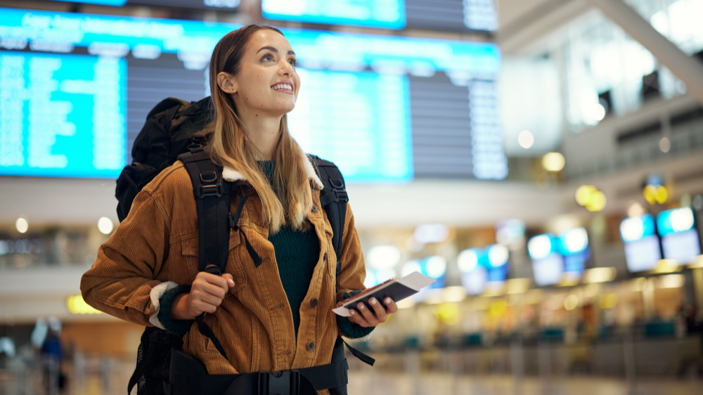 excited woman with passport at airport having  ticket and documents for immigration