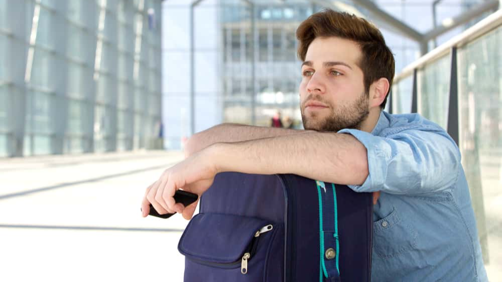 Close up portrait of a cool traveler waiting at airport with bag