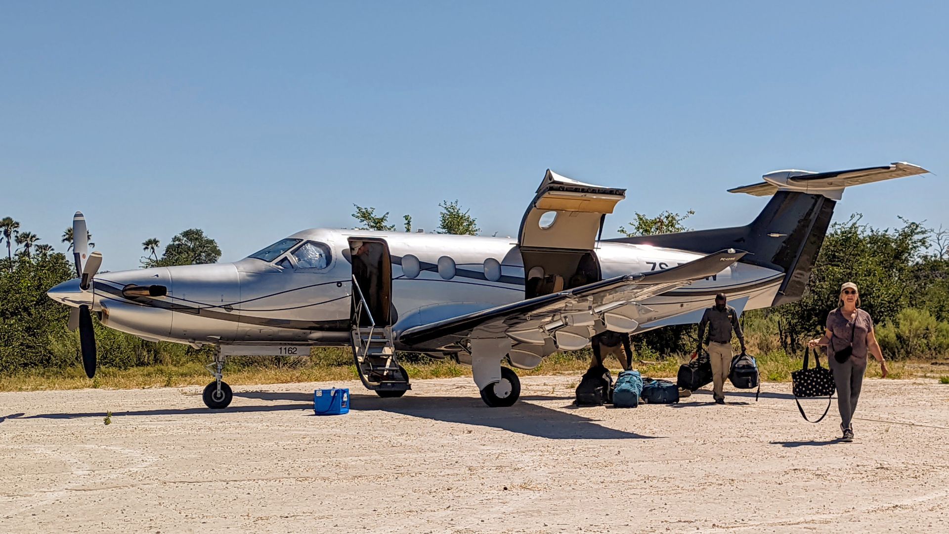 Pilatus PC-12 with South Africa registraion ZS-TSW at an airstrip near Qorokwe Camp in the Okavango Delta, Botswana, unloading passengers and gear on a safari trip organized by Chase Africa Safaris.