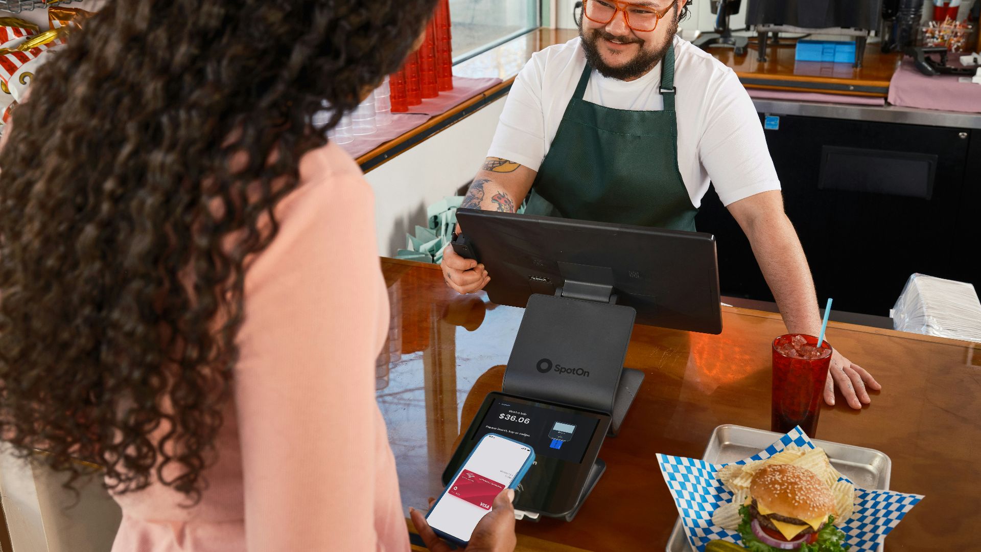 Customer pays with phone at counter with burger