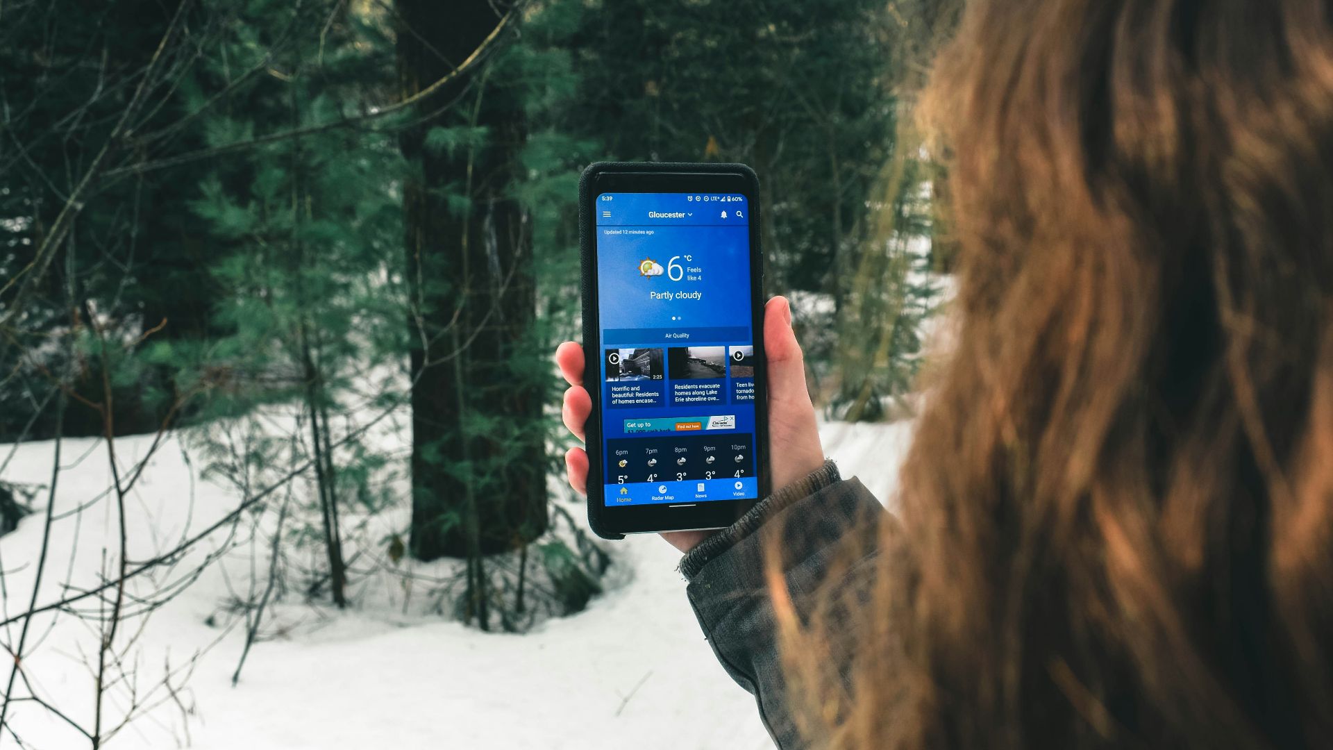 woman holding black smartphone taking photo of trees during daytime