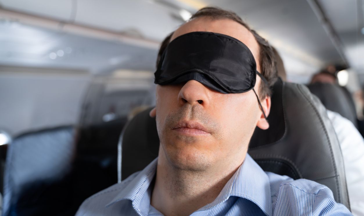 Young Man Sleeping With Sleep Mask On Airplane
