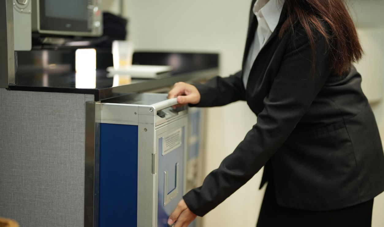On board a passenger plane: a uniformed crew member at the galley loads the service cart in the galley - a practical look at cabin crew duties, showing the work passengers rarely see.