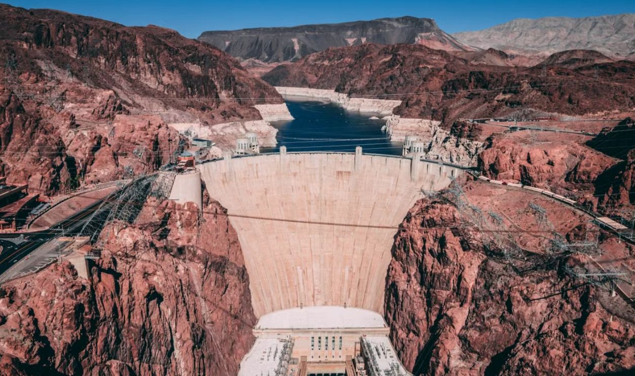 Explore breathtaking aerial view of Hoover Dam surrounded by rugged red rocks and blue sky