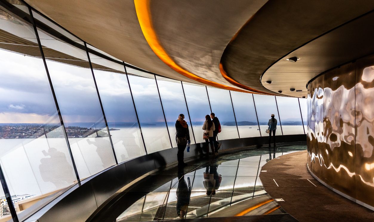 Seattle, Washington, USA - October 9, 2019: Tourists looking down through big windows to see town of seattle from observation tower, Space Needle.