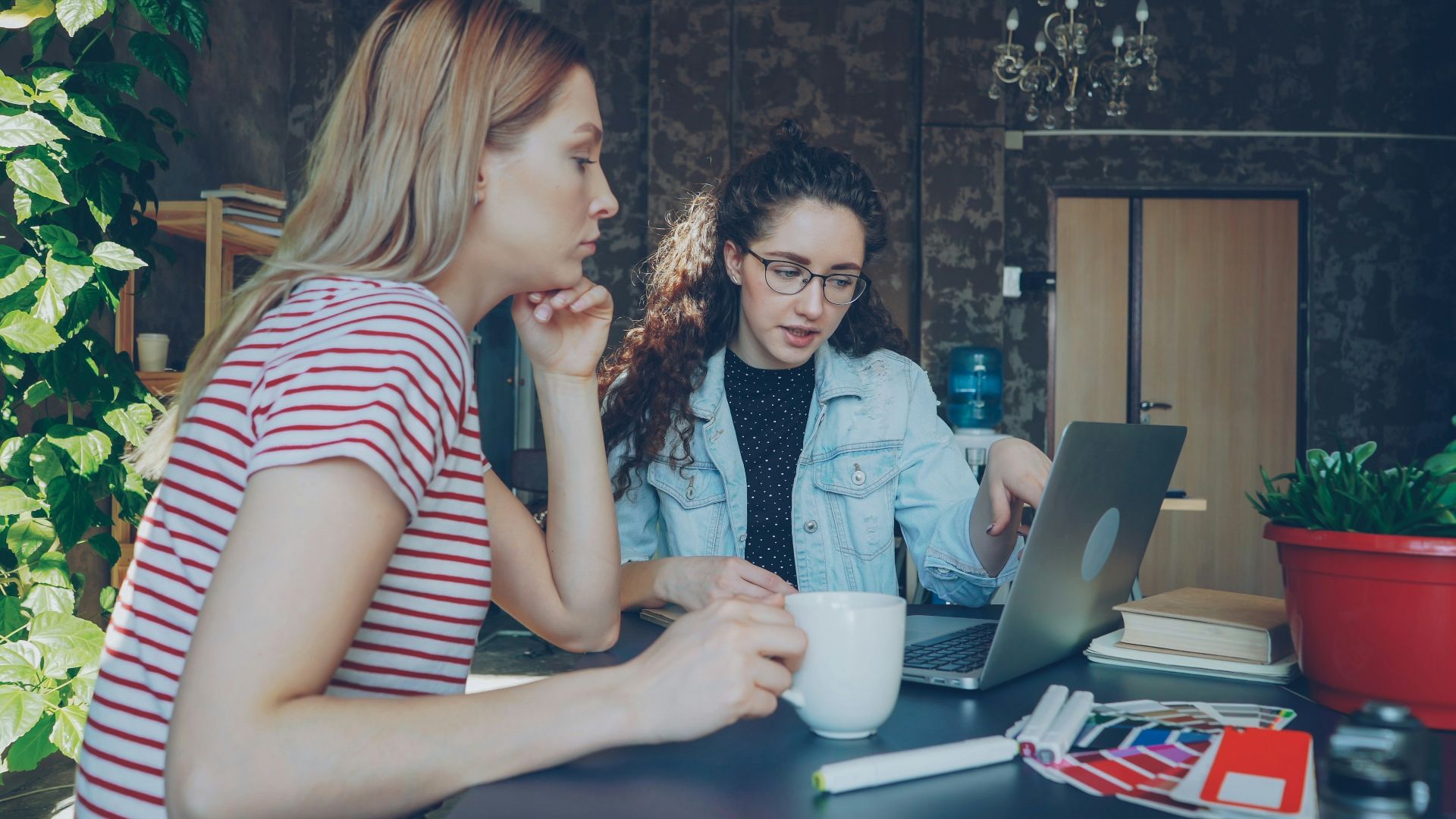 Two women discuss something on a laptop