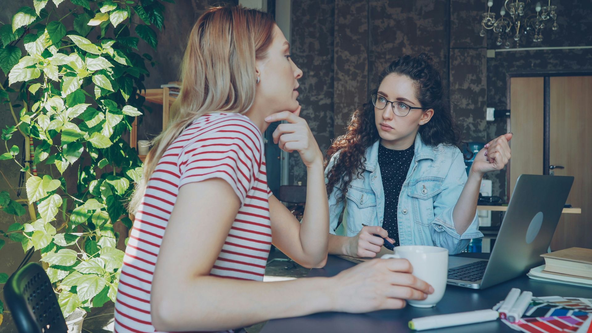 Two women are discussing something over a laptop