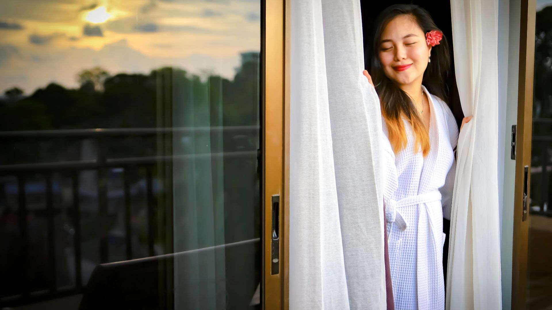 woman in white robe standing beside glass window