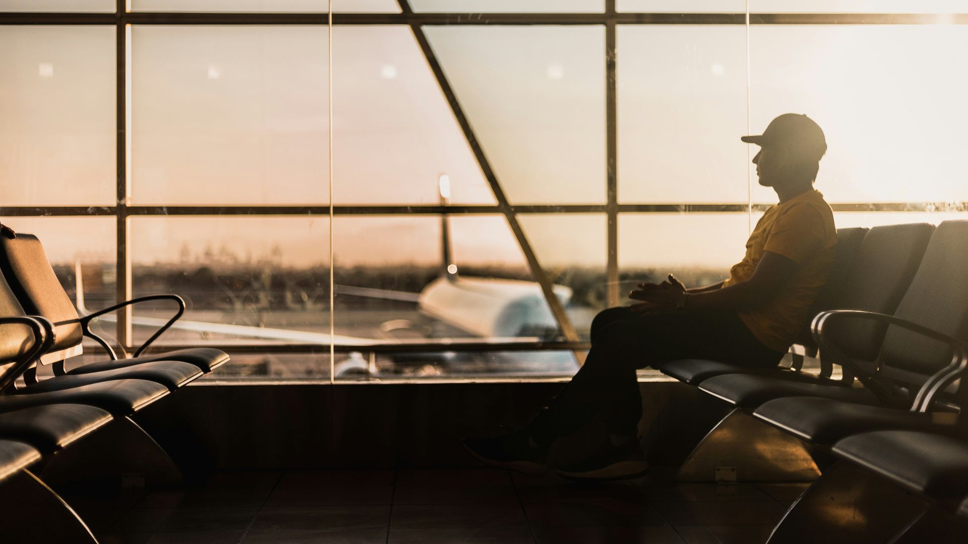 man sitting on gang chair near window