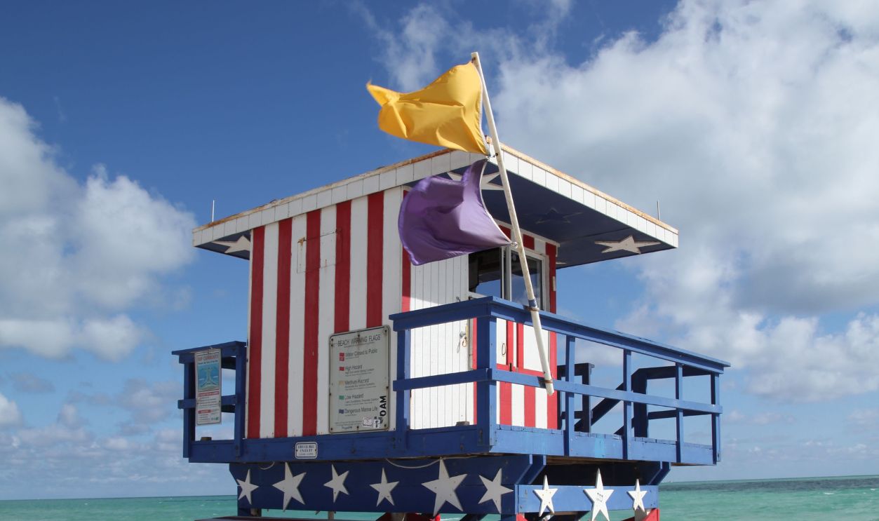 Colorful lifeguard tower on a sandy Miami beach under a bright blue sky 