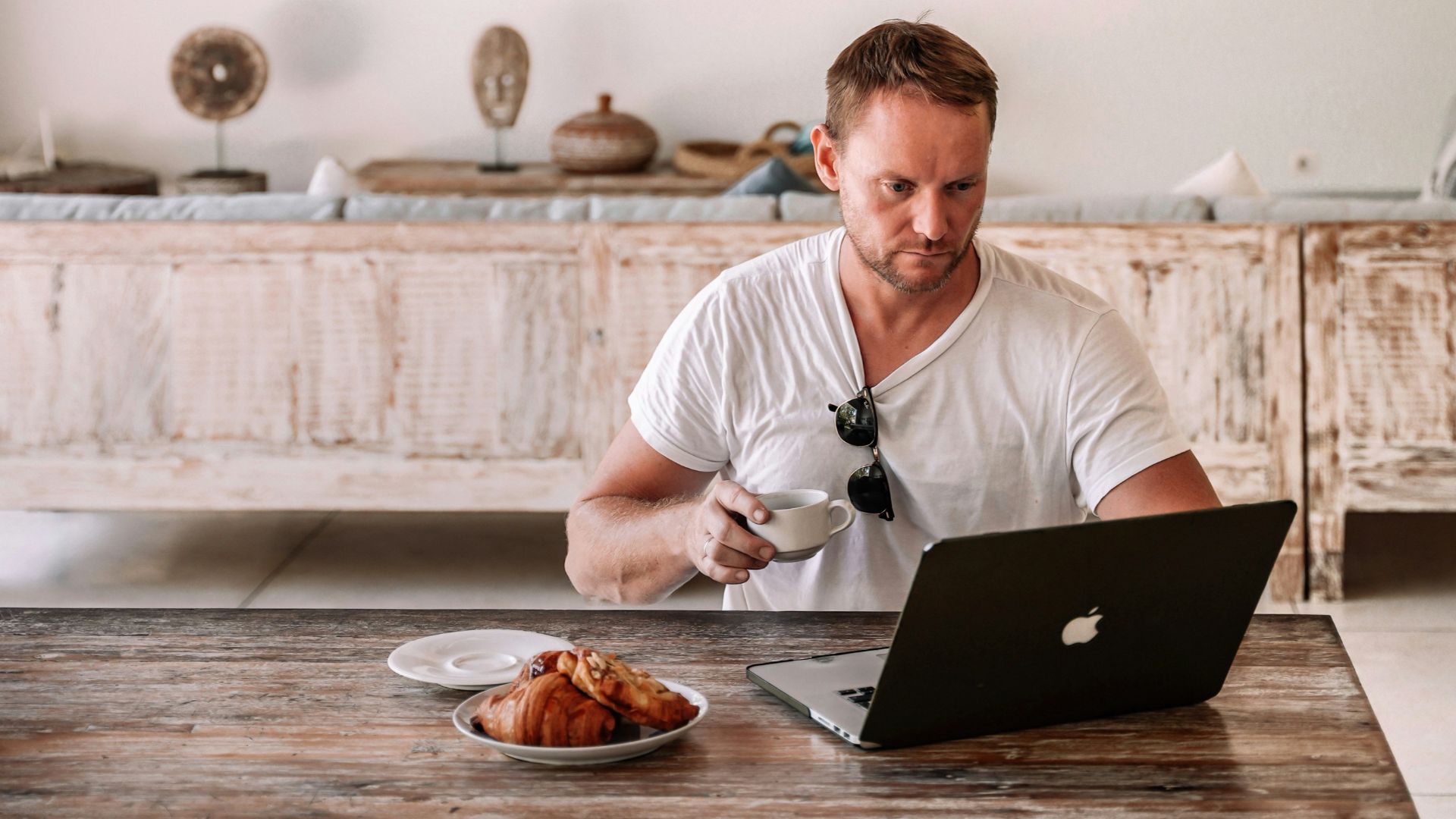 Man working on laptop with coffee and croissant