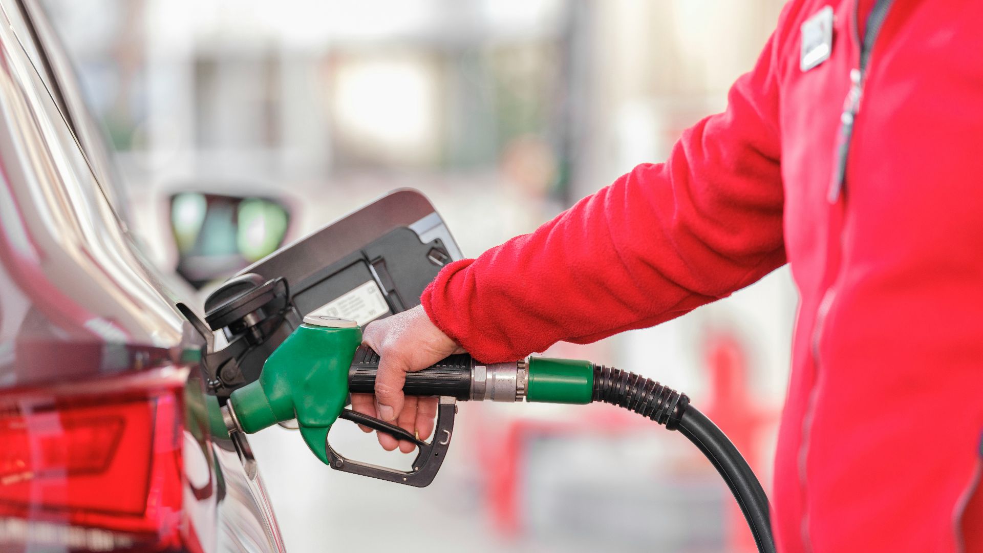 a person filling a car with gas at a gas station