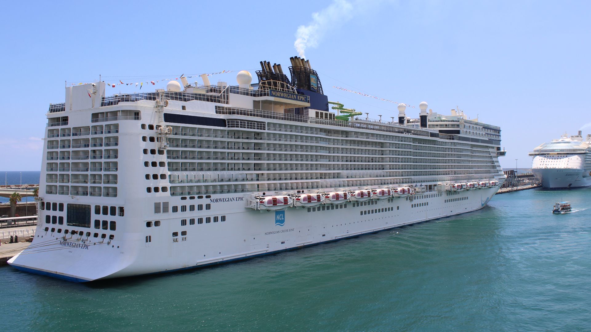 Le navire de croisière Norwegian Epic (Norwegian Cruise Line) amarré au Moll Adossat, dans le port de commerce (Barcelone), le 2 juillet 2023. Il a été construit en 2010 en France. On voit amarré derrière lui le navire de croisière Symphony of the Seas (R