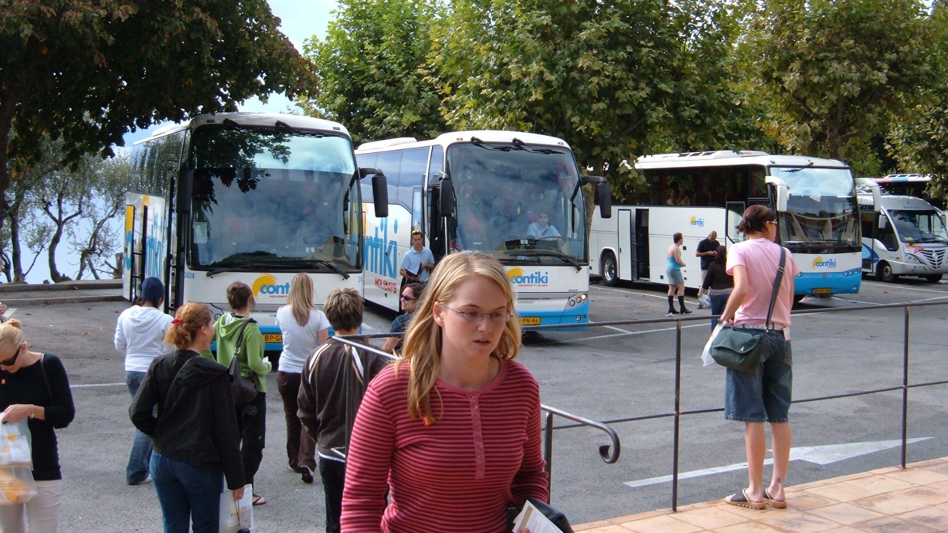 A trio of Contiki Tours buses in the parking lot of the Fragonard perfume factory in Èze, France, for three different European tours.  These buses are not limited to a specific country as Contiki has tours all over Europe.  Different tours may cross paths
