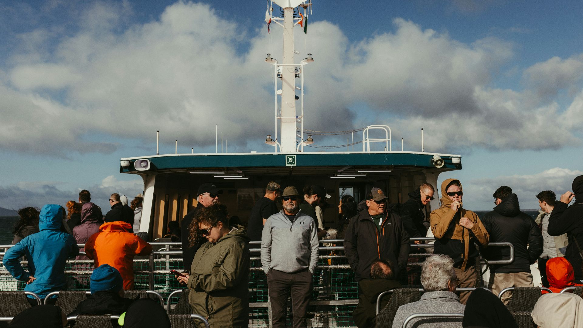 People gathered on a ferry deck under a cloudy sky