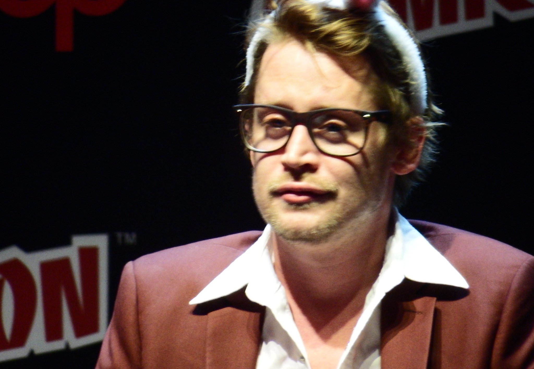 Macaulay Culkin in a red jacket and a white shirt