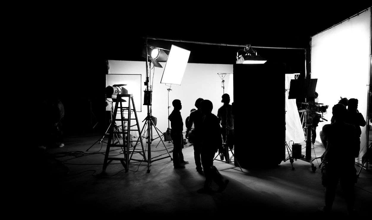 Silhouette images of video production behind the scenes or b-roll or making of TV commercial movie that film crew team lightman and cameraman working together with director in big studio