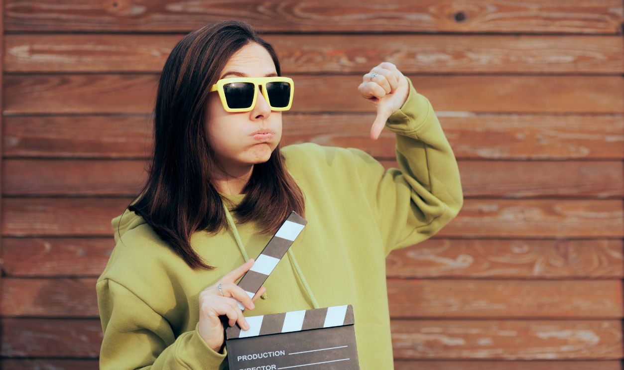 Unhappy Actress Holding Film Slate Making Thumbs Down Gesture. Movie critic feeling disappointed by nest motion picture