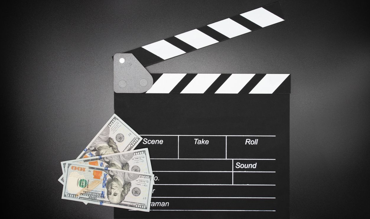 Cinema clapper board and money, film production expenses, Hollywood budgeting, Movie clapperboard and cash, production costs, entertainment industry finances